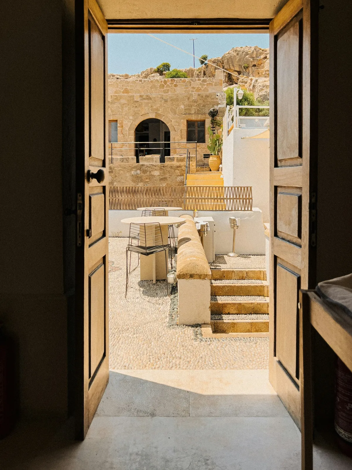 Puerta abierta hacia un patio de piedra mediterráneo, luz cálida