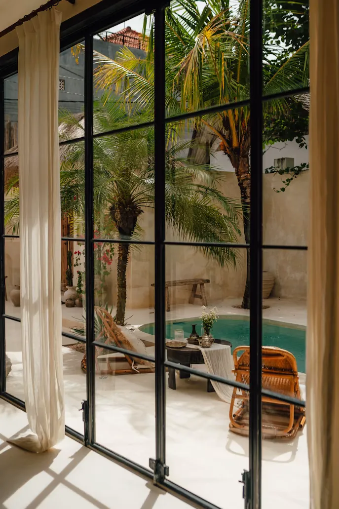 Patio mediterráneo con piscina, palmeras y puertas de hierro y cristal