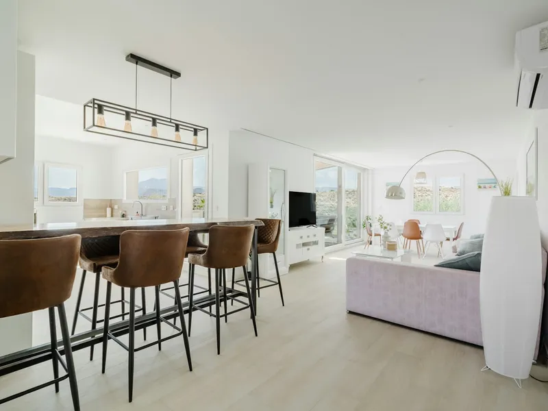 [[ Reference photo — replace with a real photo of the penthouse ]] Bright living room with open kitchen and light wood floors
