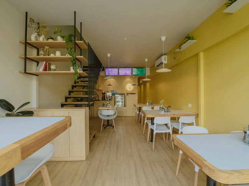 [[ Reference photo — replace with a real photo of the premises ]] Warm interior of a small shop with wooden tables